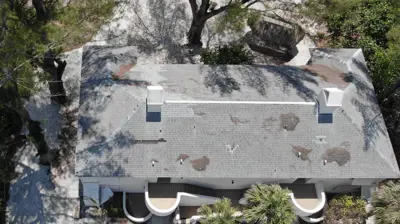 Aerial view of a Florida home in Sarasota showing signs of poor roof installation, including uneven shingles and rusted nail heads.