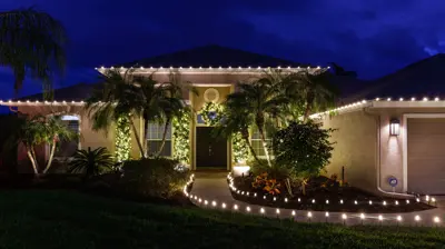 Florida home with palm trees decorated with holiday lights and roofline lighting for Christmas