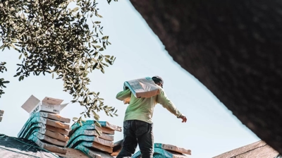 man carrying underlayment on a roof