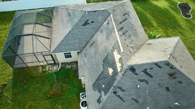 Aerial view of a Florida home with severe shingle damage after a storm, showing missing and torn roofing materials.