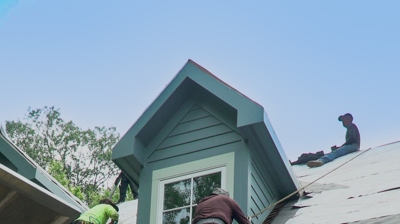 Roof installers work on a roof replacement in Johnston, RI