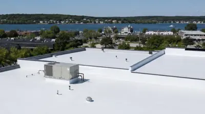 Aerial view of a Rhode Island commercial low-slope roof with white TPO membrane and roof drains.