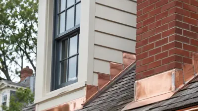 Custom soldered copper chimney flashing and copper gutters on a premium roof replacement in Providence, Rhode Island.