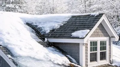 Snow-covered Rhode Island home with visible ice dam at roof edge, long icicles hanging from eaves, and potential hidden roof damage from winter moisture and snowmelt buildup