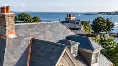 Drone view of a Rhode Island historic home with slate-style roofing and copper flashing