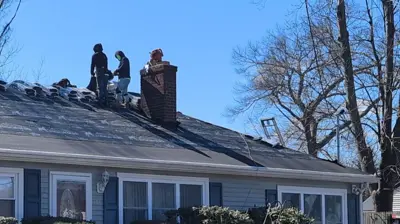 Roof replacement in Rhode Island with Mighty Dog Roofing of Rhode Island contractors installing a new asphalt shingle roof on a residential home with chimney and ventilation system