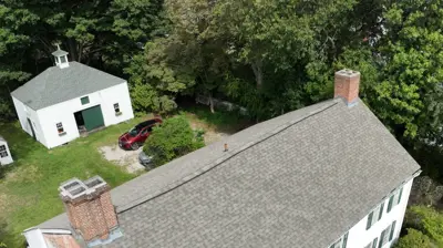Historic stone-ender house in North Providence, Rhode Island with a newly restored roof and large fieldstone chimney end wall.