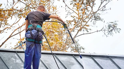 Skilled roofer performing pre-winter roof cleaning