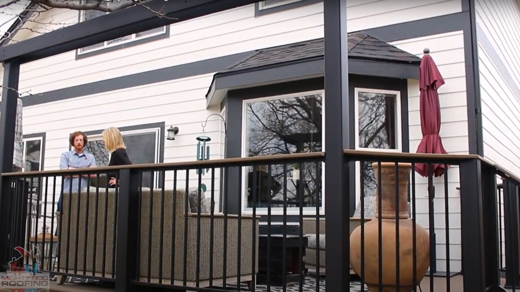 Two people stand on a porch