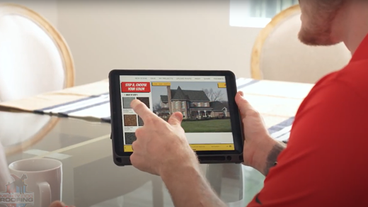 A person holds and points at a tablet that displays the Mighty Dog Roofing website