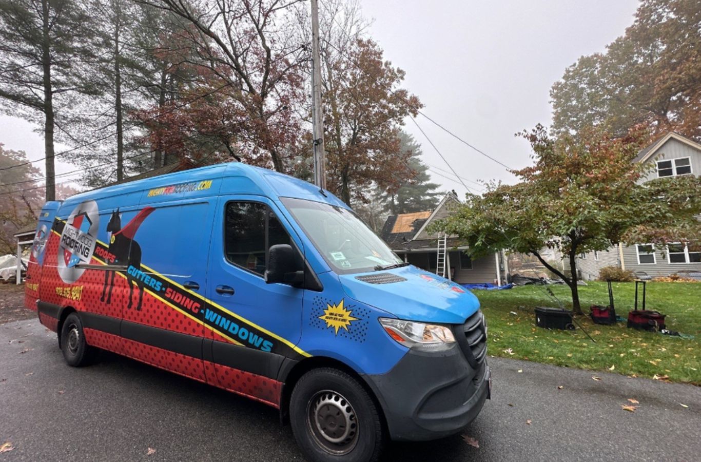 A Mighty Dog Roofing crew cutting and fitting gutters on-site in Bedford, MA to provide a custom, leak-free system for lasting durability.