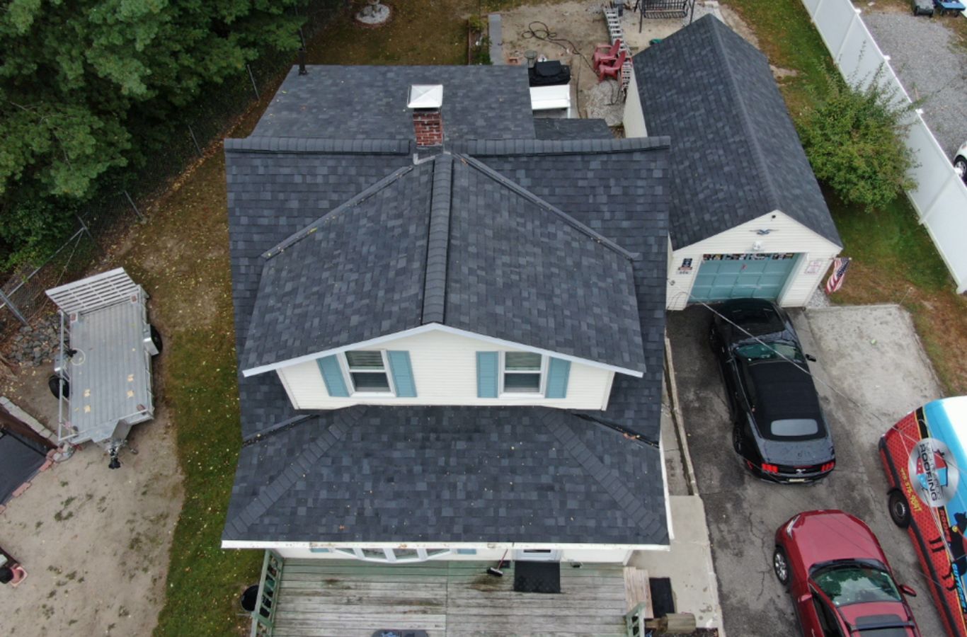 A Mighty Dog Roofing crew cutting and aligning gutter sections in Dunstable, MA to improve flow and reduce future maintenance.