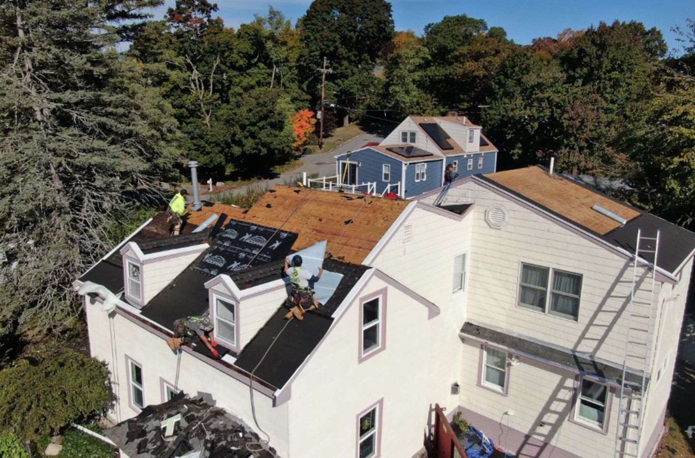 Mighty Dog Roofing professionals performing roof tear-off in Chelmsford, MA, showing the advantages of hiring an experienced roofing company.