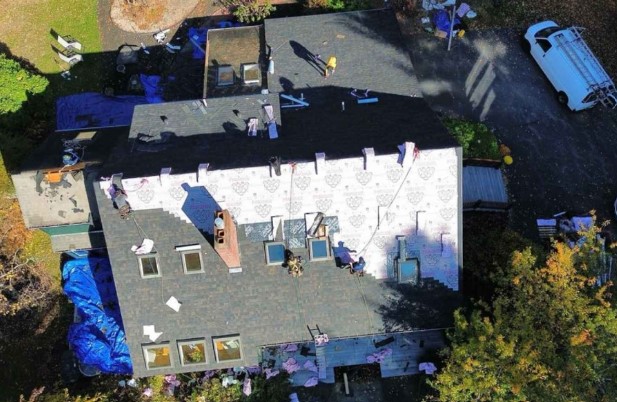 A Mighty Dog Roofing professional performing a roof inspection in Groton, MA for residential service needs.