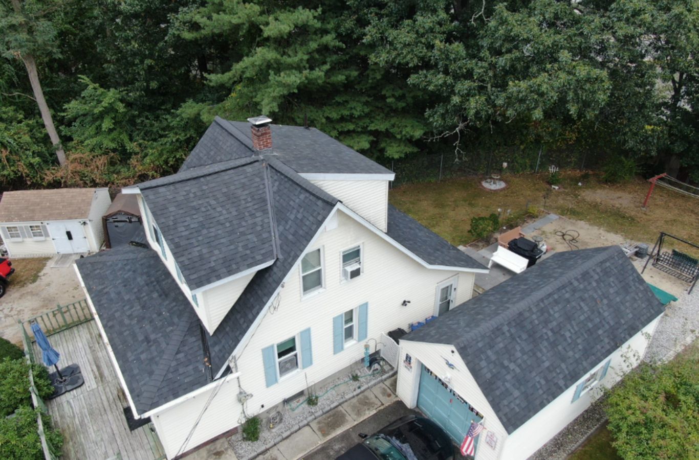 A Mighty Dog Roofing team member installing seamless gutters on a Harvard, MA home to manage rainwater and protect against foundation damage.