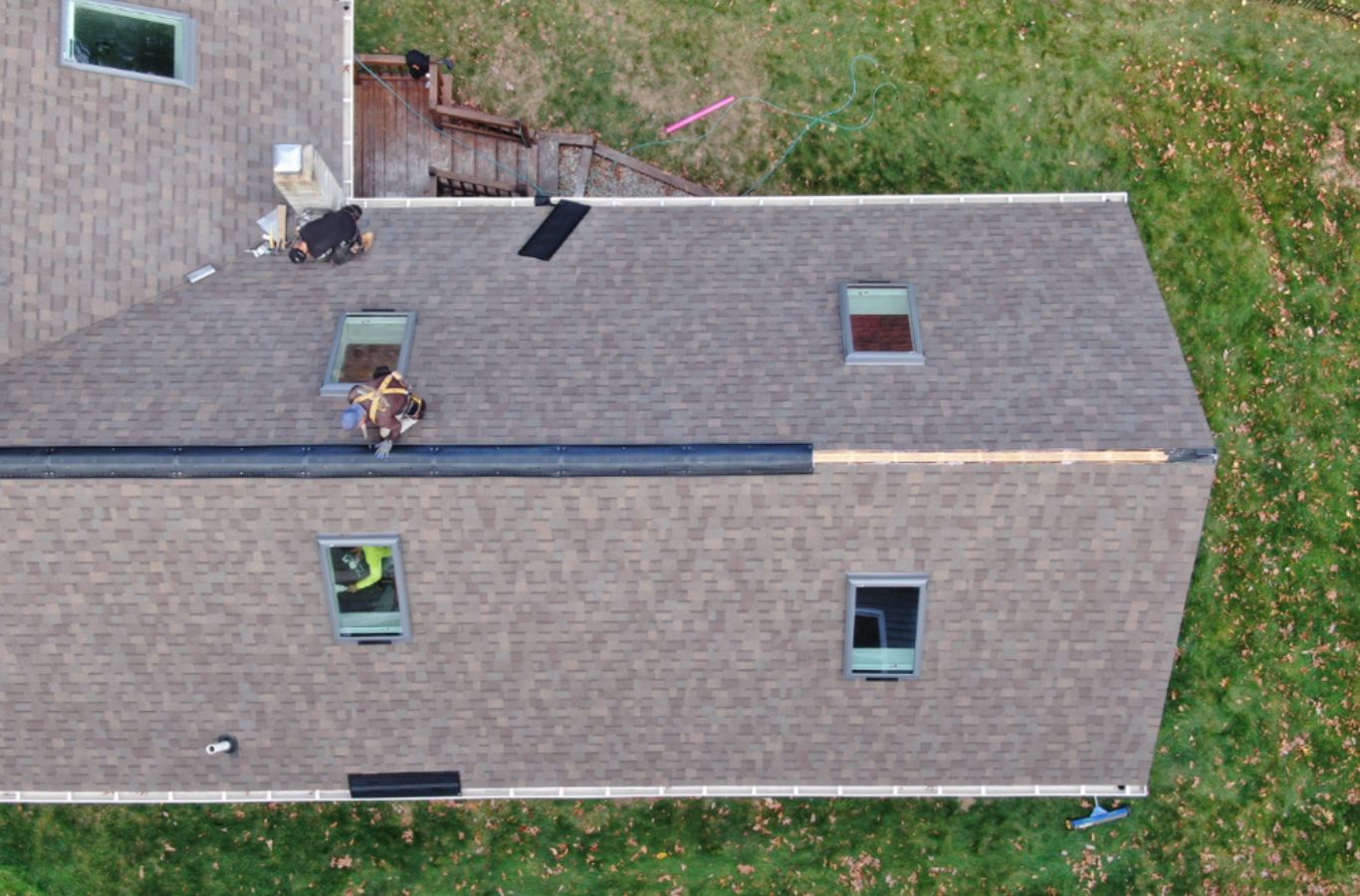 A Mighty Dog Roofing specialist installing seamless gutters on a Lincoln, MA home to prevent overflow and protect against water damage.