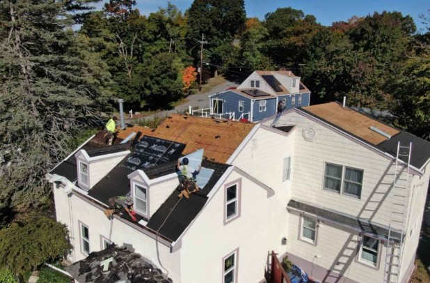 Roofer from Mighty Dog Roofing assessing a roof in Waltham, MA.