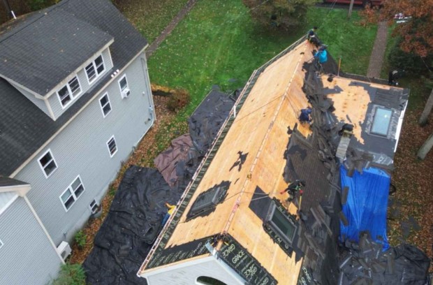 Roofing team installing underlayment on a residential roof in Waltham, MA.