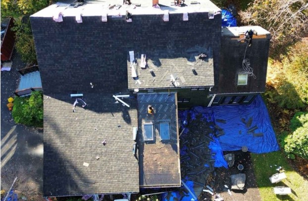 Skilled roofer from Mighty Dog Roofing working on a rooftop in Groton, MA, emphasizing benefits of expert roofing.