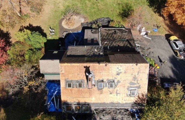 Roofing team from Mighty Dog Roofing installing shingles on a Groton, MA rooftop with expert care. Roofing Company near me.