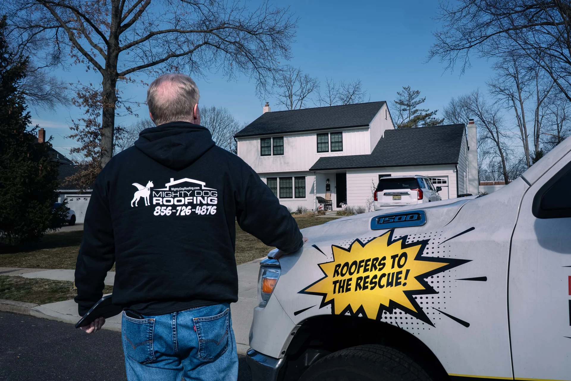 Mighty Dog Roofing of South Jersey team member reviewing a residential roofing project in front of a home
