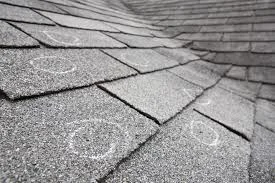 Close-up of hail impact damage on asphalt shingles on a Golden, CO home with foothills visible in background