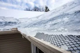 Heavy snow load on a Denver, CO residential roof during winter with ice dam formation visible at the eave