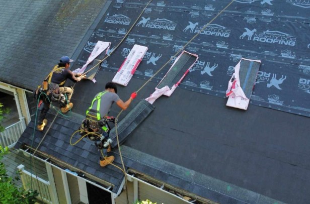 A Mighty Dog Roofing expert inspecting a home in Ayer, MA, using professional equipment for top-tier roofing service.
