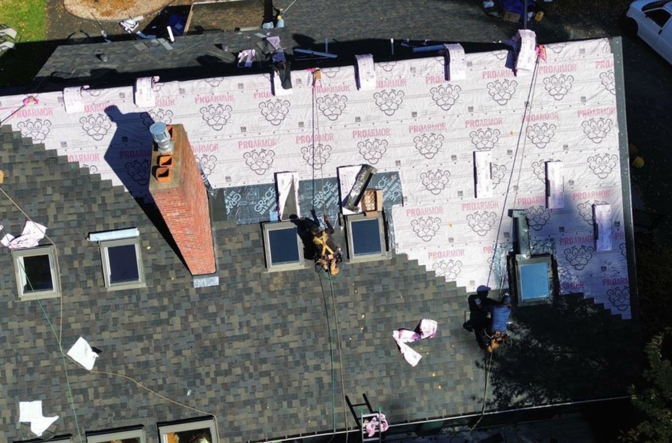Roofers from Mighty Dog Roofing adding finishing touches on a new roof in Lexington, MA, reflecting the value of hiring trusted local pros.