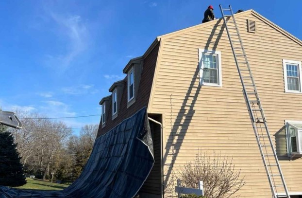 Roofer installing new shingles in Carlisle, MA using premium materials.