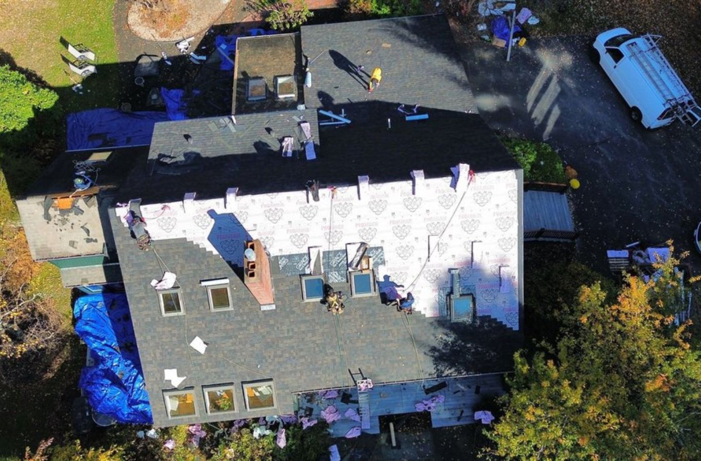 An overhead shot of Mighty Dog Roofing of Greater Middlesex County performing a roof replacement in Acton, MA, showcasing professionalism and care on every job.