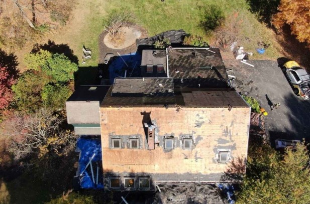 Roofer replacing asphalt shingles on a Dunstable, MA home during a maintenance visit.