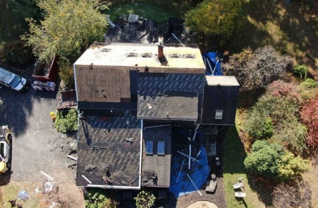 A professional roofer working on a residential property in Harvard, MA, ensuring a weatherproof installation.
