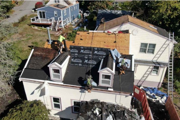 A roofing team member placing shingles on a Harvard, MA home with precision and care.