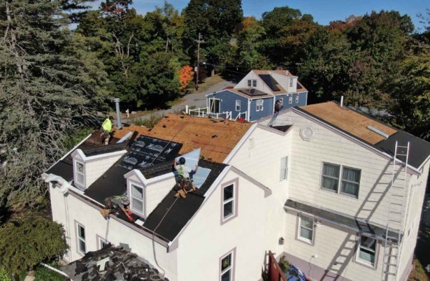 A roofing technician from Mighty Dog Roofing applying shingles in Stow, MA, highlighting professional service.