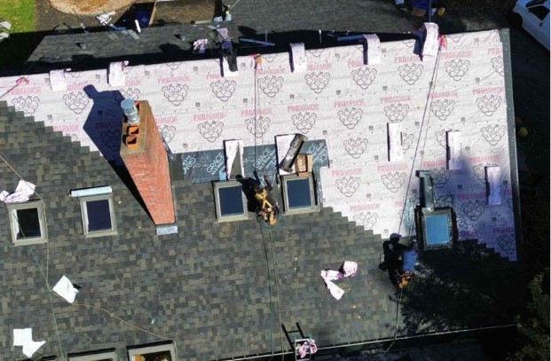 Roofer applying sealant to a roof in Tyngsborough, MA during a scheduled repair visit.