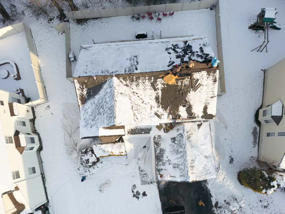 Snow and ice buildup on a residential roof in Gloucester County NJ showing exposed areas during winter storm conditions