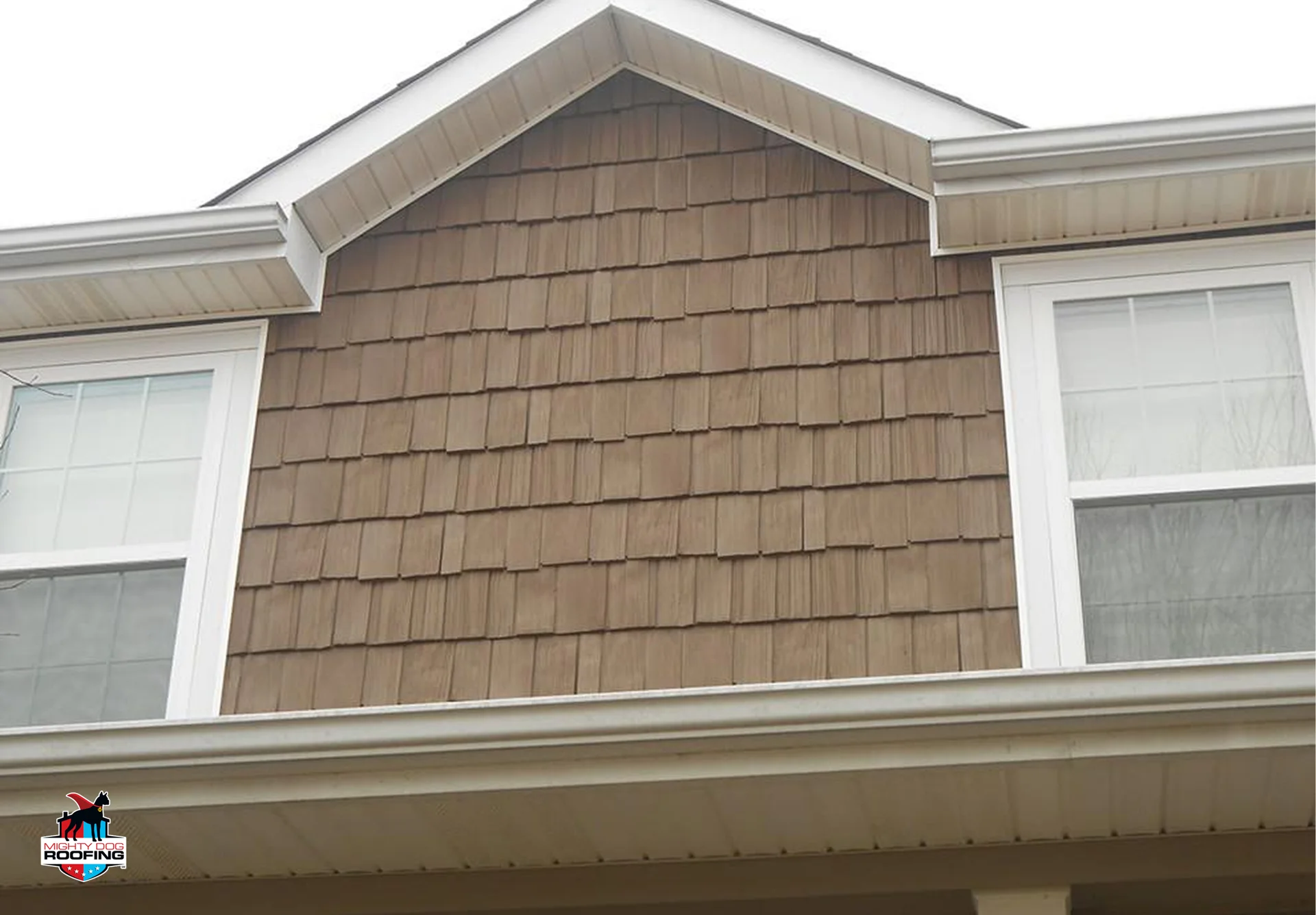 Brown vinyl shake siding in a gable above beige lap siding